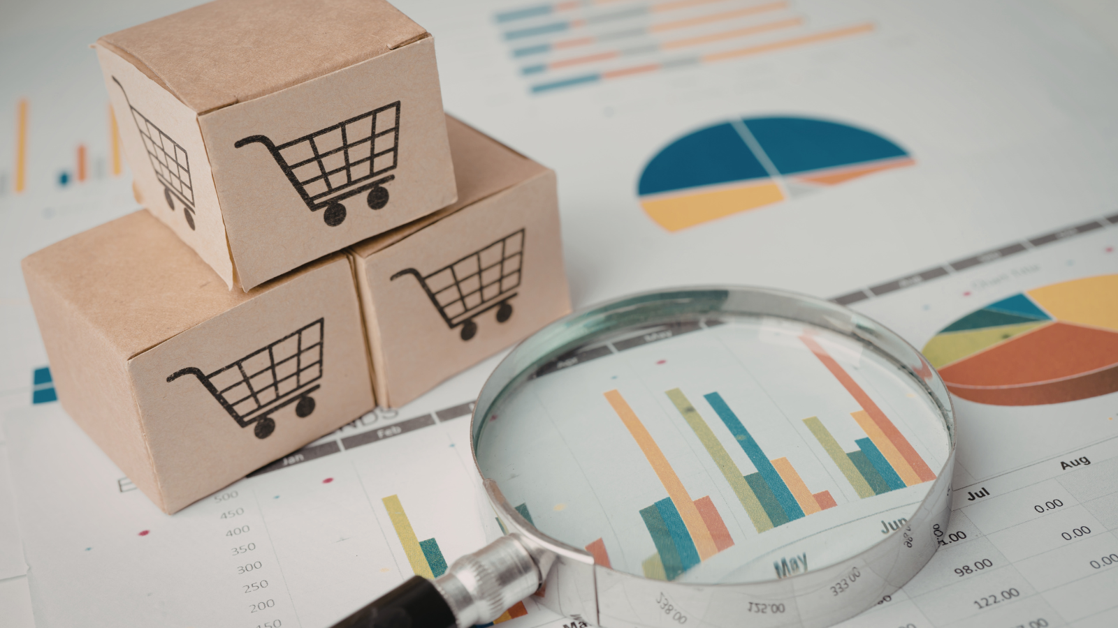 Magnifying glass over ecommerce sales charts with package boxes, representing hidden costs that quietly erode e-commerce margins.