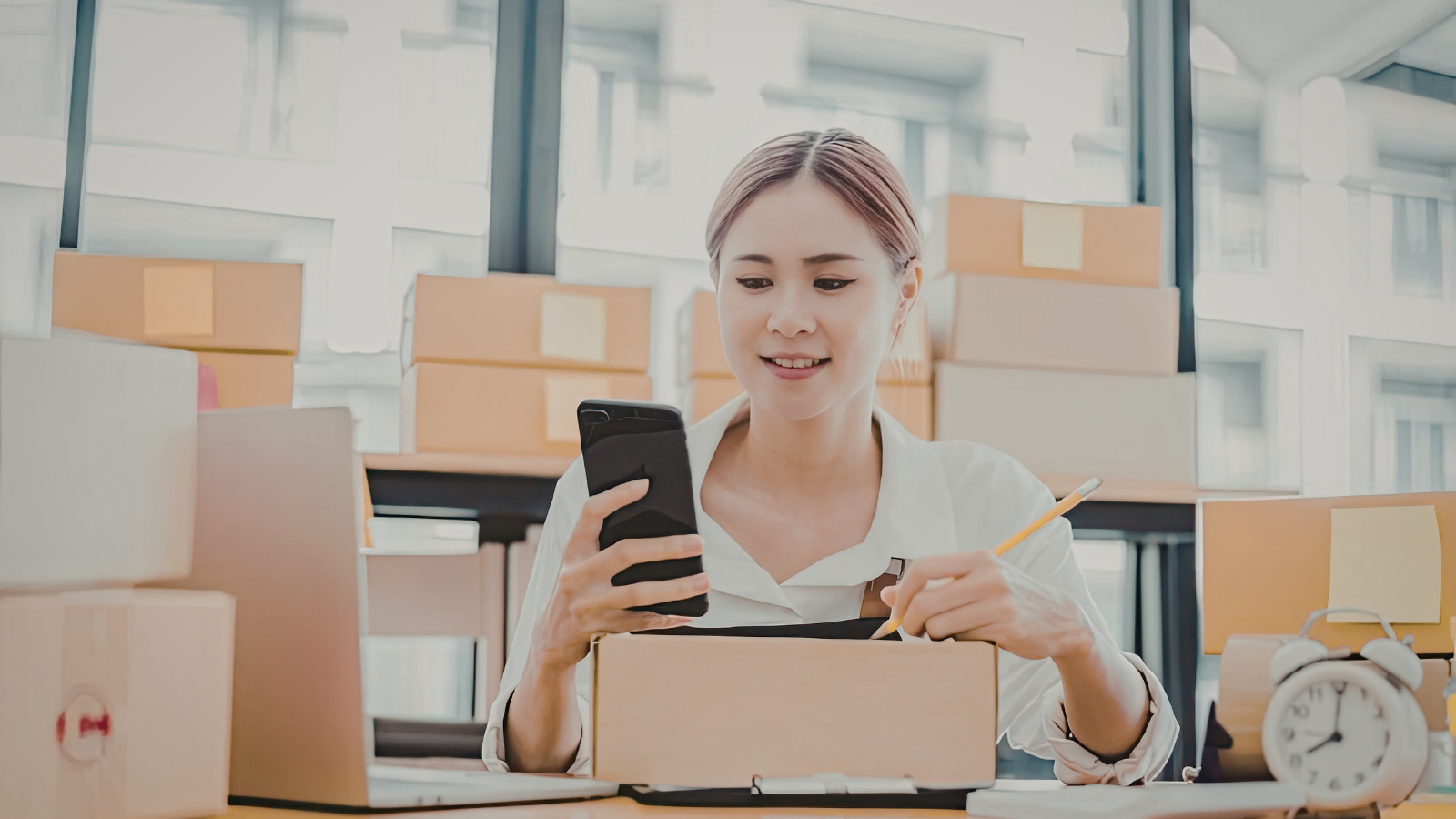 returns management ecommerce woman checking package with mobile warehouse background
