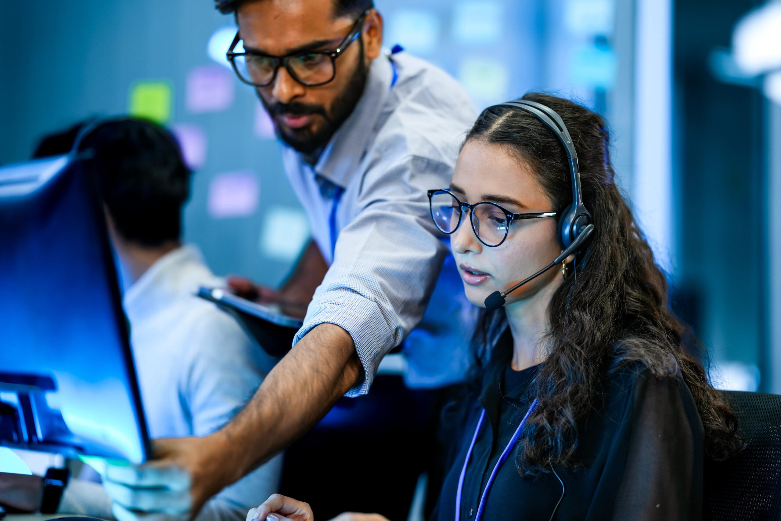 Ecommerce operations team reviewing orders on a computer, one team member wearing a headset