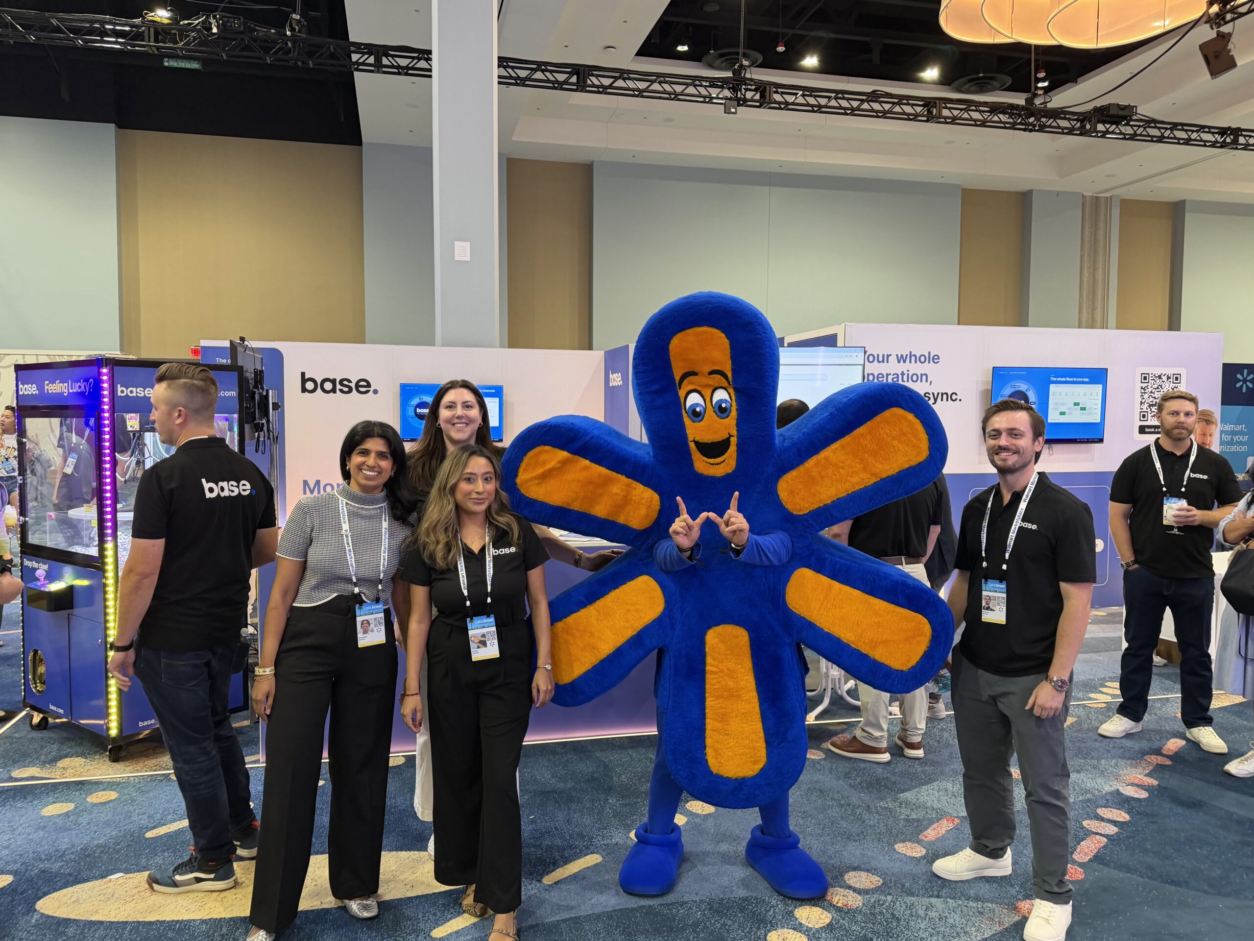 Base team members posing with the Walmart spark mascot at booth 1602