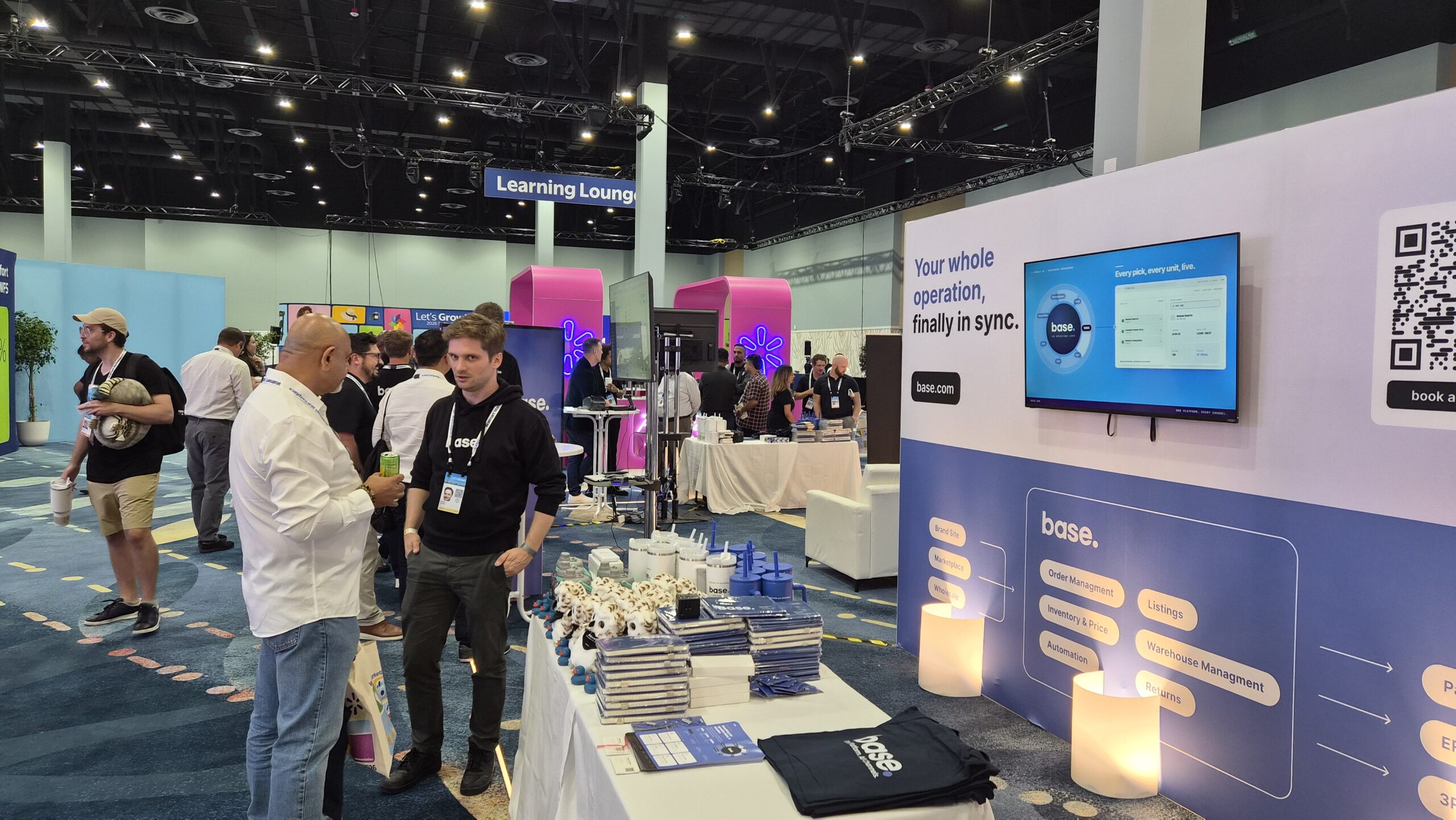 Conversations at the Base booth with the swag table and product screens visible