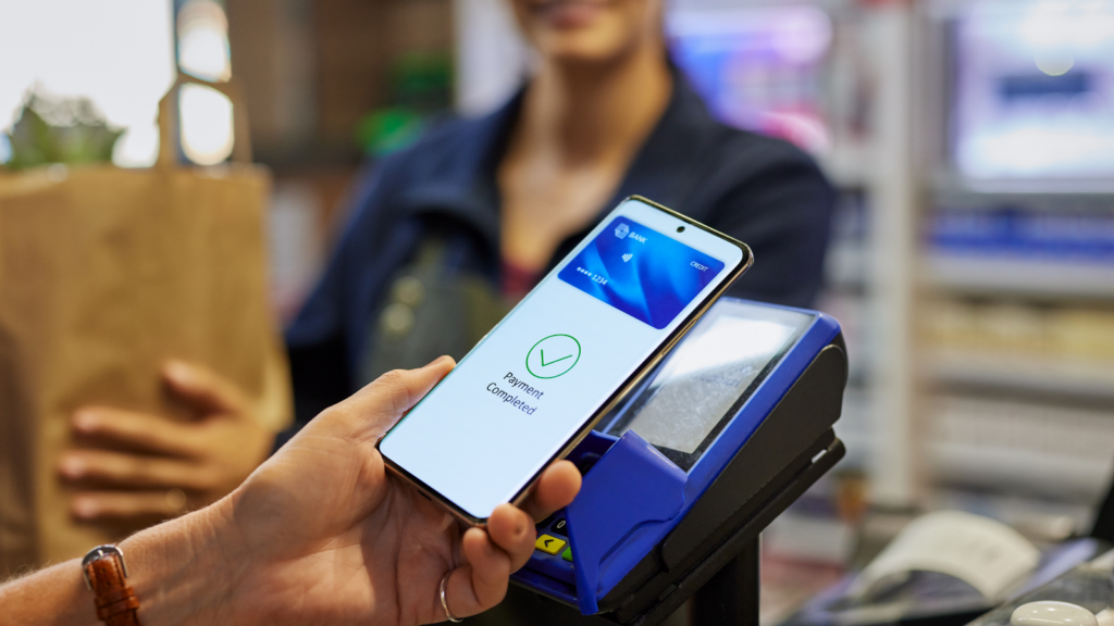 Customer making a digital payment at checkout using a smartphone and POS terminal