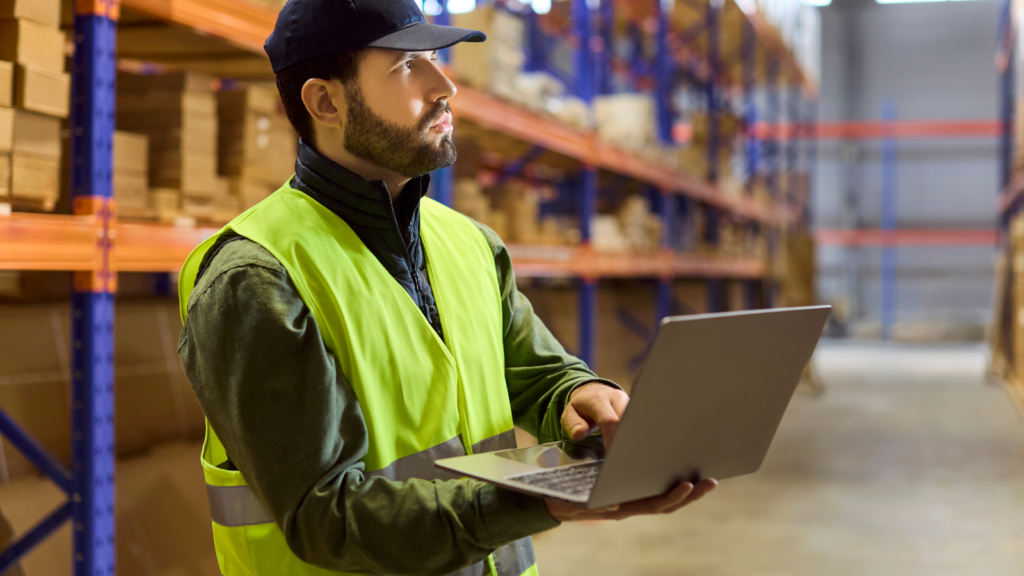 Warehouse worker using a tablet to manage and monitor inventory in a storage facility
