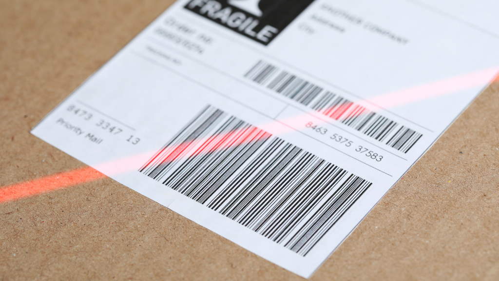 Barcode scanning on warehouse packages showing how barcode and RFID technology supports accurate inventory handling