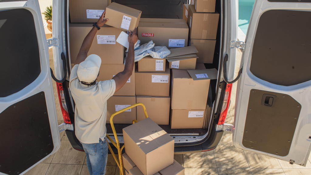 Delivery and last-mile logistics scene showing a worker loading ecommerce packages into a delivery van for customer dispatch