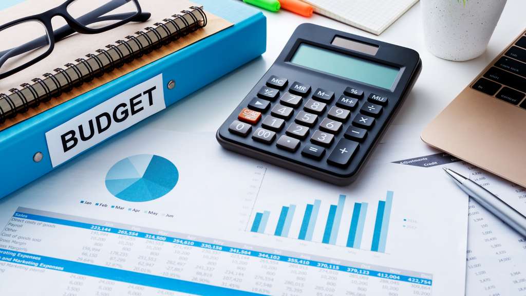 Inventory migration budget planning with a calculator, financial charts, and a notebook representing the costs of software, implementation, hardware, and staff training.