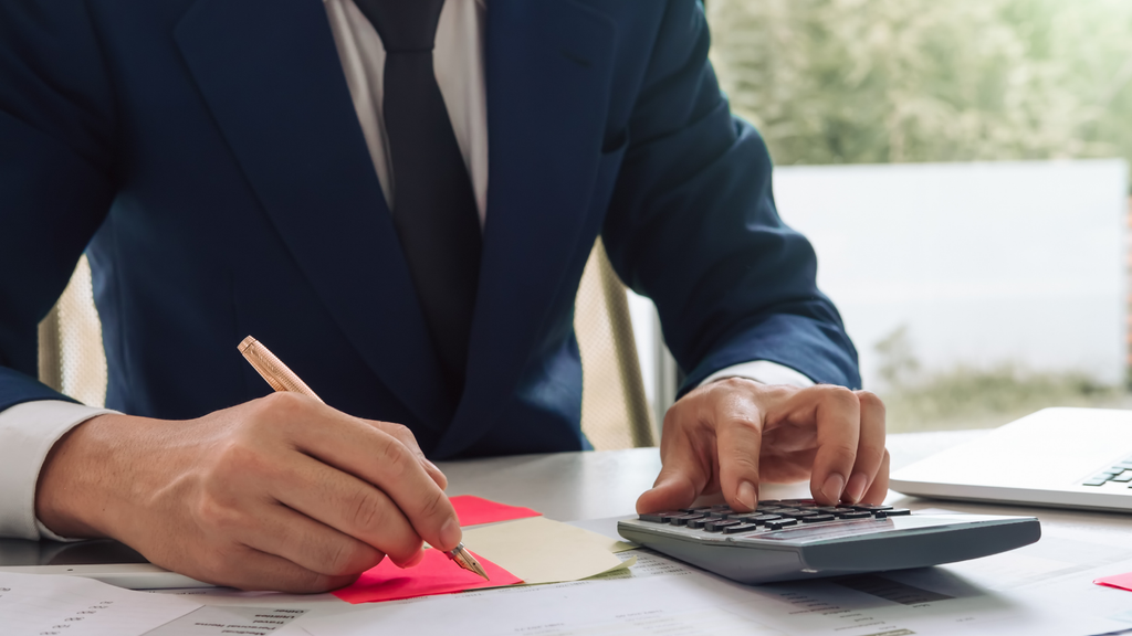 Business professional using a calculator and paperwork to review shipping costs and courier allocation expenses.