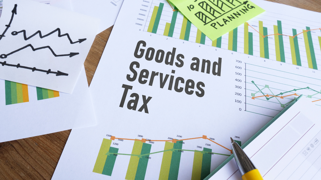 Photograph of GST documents, financial charts, graphs, and a pen representing tax reporting and financial analysis.