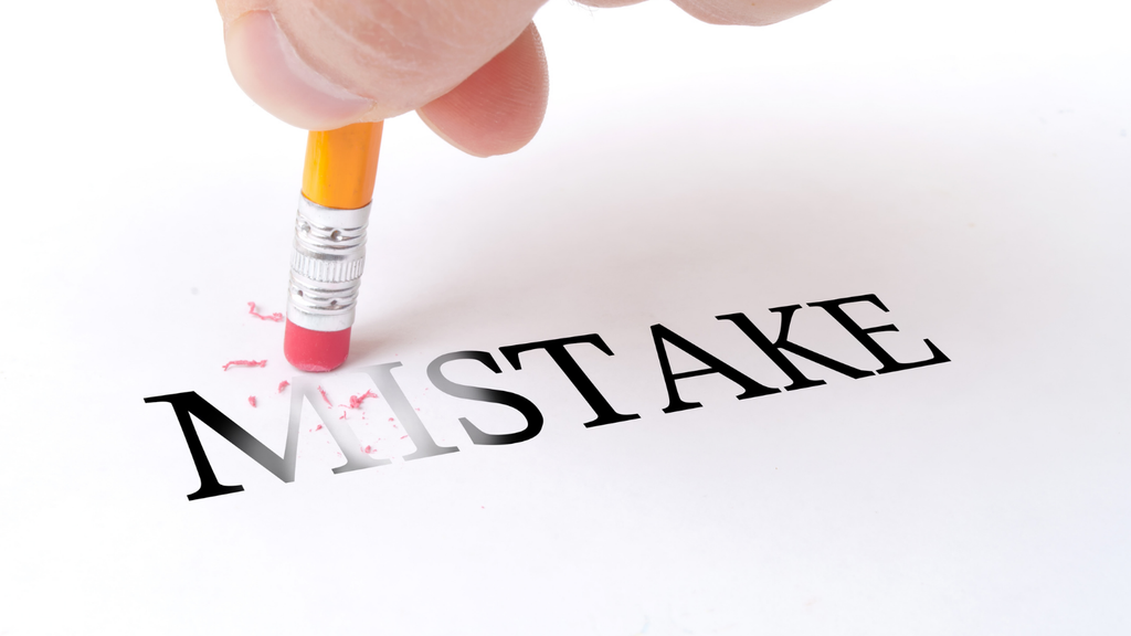 Photograph of a hand erasing the word “MISTAKE” from paper, representing the prevention of errors during SAP integration projects.
