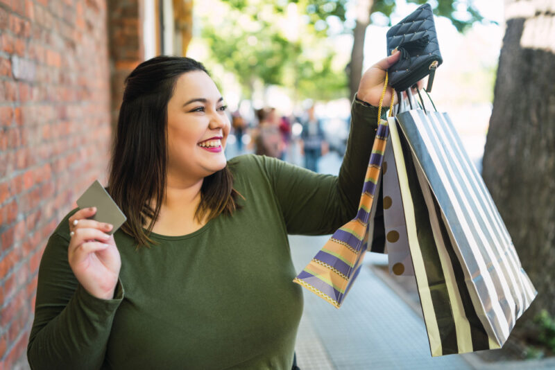 Mujer feliz sosteniendo tarjeta de crédito y bolsas de compras
