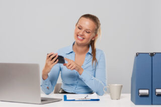 Una mujer feliz sostiene su teléfono celular y demuestra lo fácil que es administrar el flujo de efectivo utilizando la funcionalidad Base