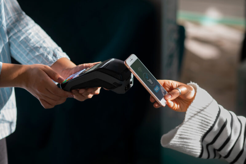 Persona pagando con tecnología NFC en un restaurante.