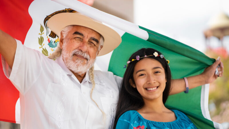 Familia sonriente con bandera mexicana vista frontal